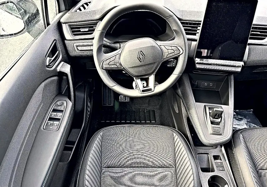 Vue intérieure centrée sur le volant et la console centrale du Renault Symbioz gris, avec écran tactile vertical et commandes au volant.