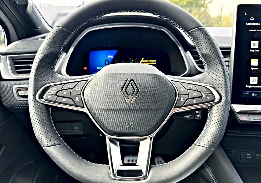 Vue rapprochée du volant noir perforé de la Renault Symbioz 2026 avec commandes multifonctions et logo central chromé.