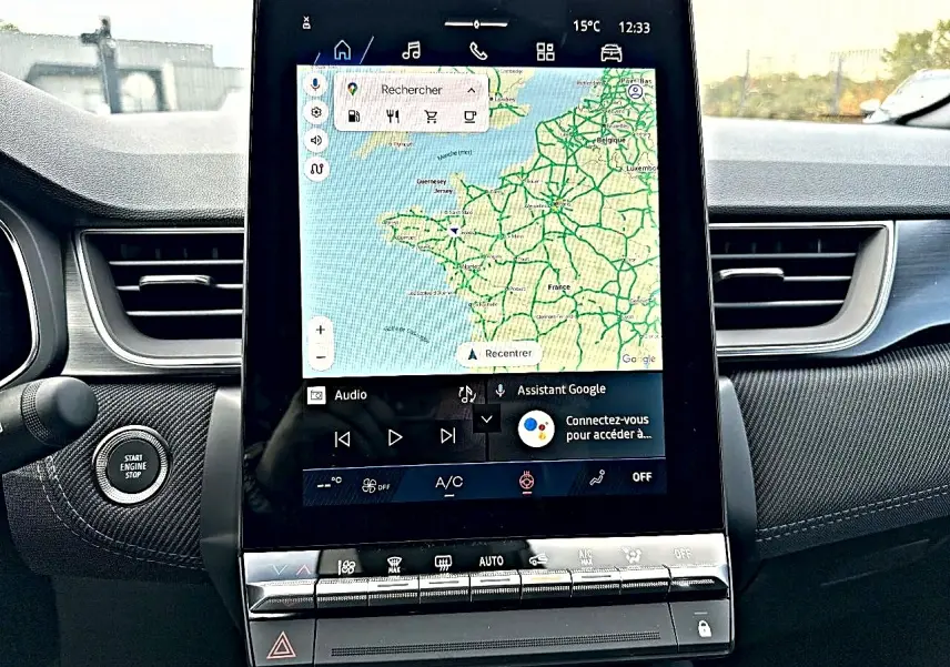 Vue intérieure centrée sur l'écran tactile du tableau de bord de la Renault Symbioz gris rafale avec commandes clim et bouton start/stop.