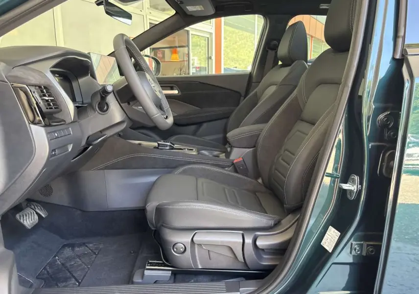 Vue côté gauche de l’intérieur du Nissan Qashqai E-POWER 205 N-DESIGN vert cayuga, sièges cuir alcantara noirs et tableau de bord moderne.