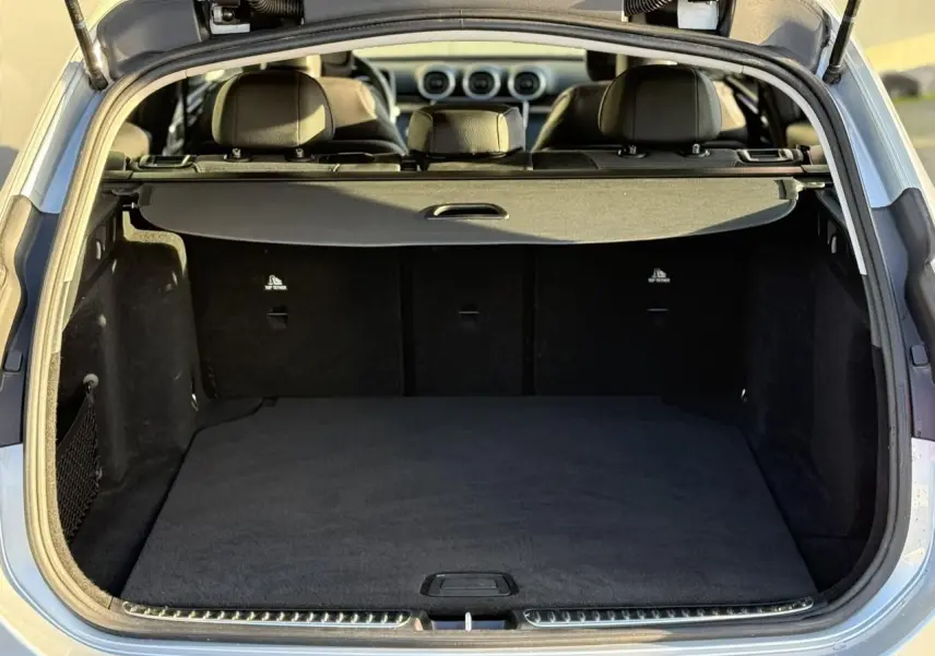 Coffre ouvert vu de l'arrière d'un Mercedes Classe C Break argent High-Tech, intérieur noir et cache-bagages déployé.
