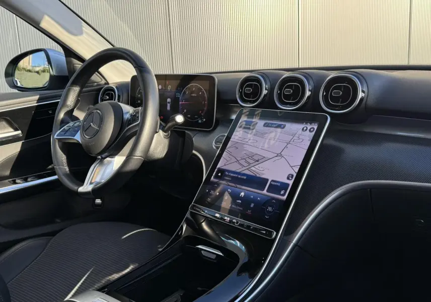 Vue intérieure avant du tableau de bord et volant Mercedes Classe C Break V 200d 2023 avec écran tactile vertical et finition noir brillant