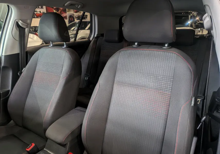 Gros plan sur les sièges avant en tissu noir avec surpiqûres rouges de la Volkswagen Golf VII TSI 125 CH Sound blanche.