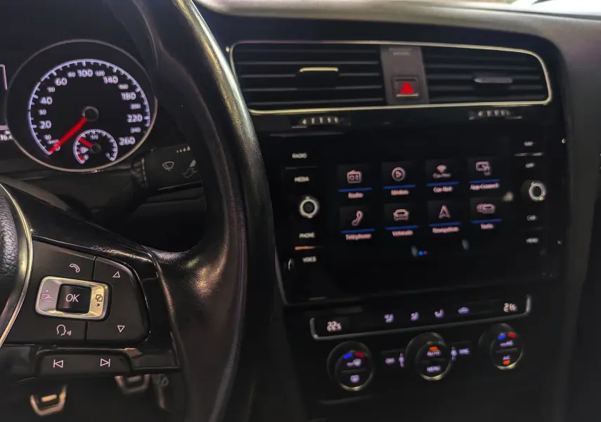 Vue rapprochée du tableau de bord noir de la Volkswagen Golf VII TSI 125 CH avec écran tactile et commandes au volant.