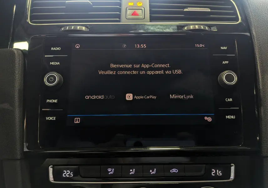 Vue rapprochée de l'écran tactile central noir du Volkswagen Golf VII blanc, affichant App-Connect et commandes climatisation.