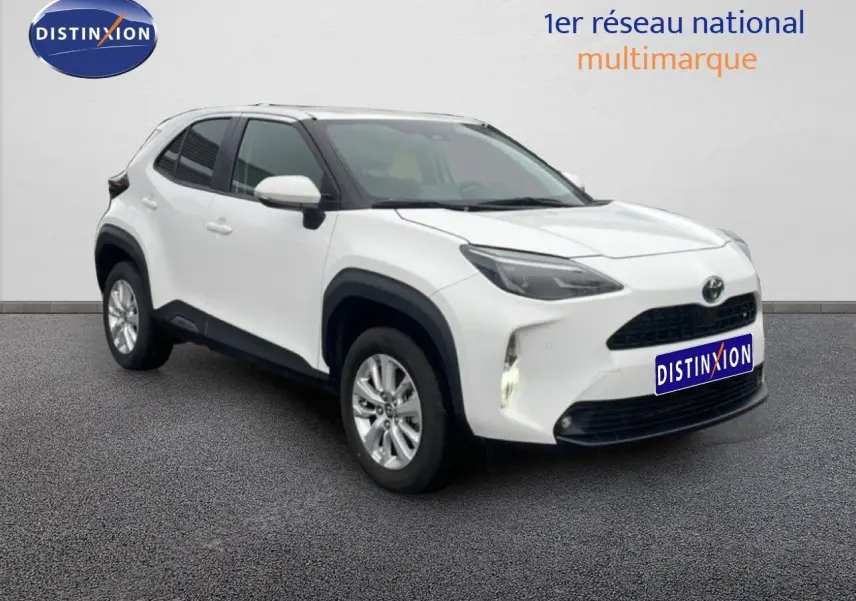 Toyota Yaris Cross blanc en 3/4 avant droit, avec calandre noire et protections d'ailes noires visibles.