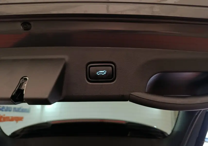 Bouton d'ouverture électrique du coffre vu de l'intérieur du hayon d'un Hyundai Tucson gris foncé 2025.