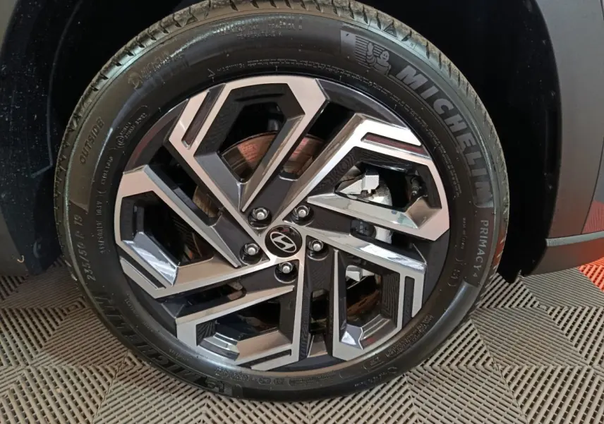 Gros plan sur la roue avant droite du Hyundai Tucson gris foncé, jante alliage au design géométrique moderne.