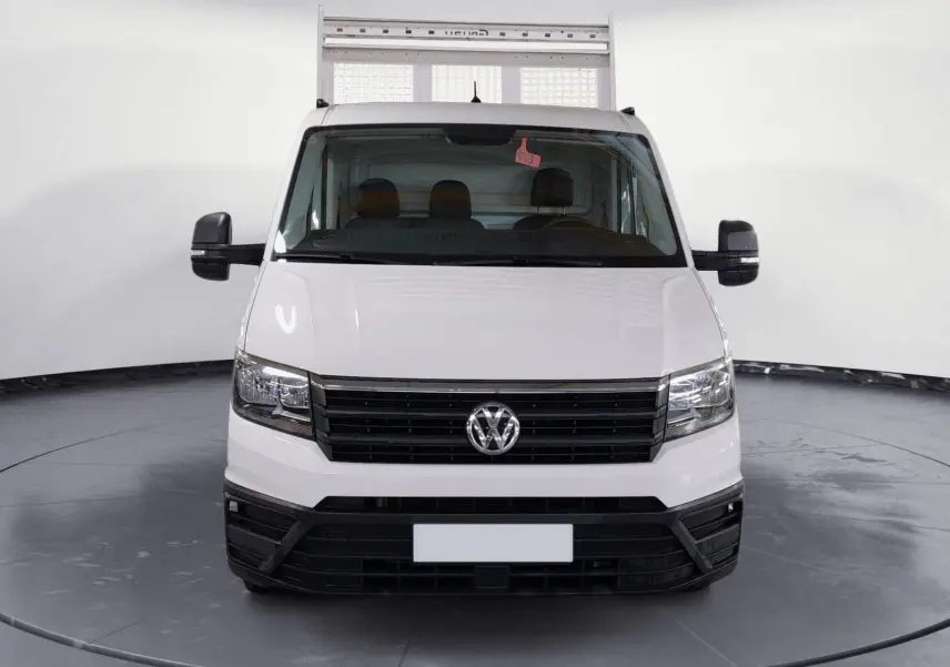 Vue frontale d'un Volkswagen Crafter Chassis Cabine blanc avec benne et coffre, calandre noire et rétroviseurs noirs.
