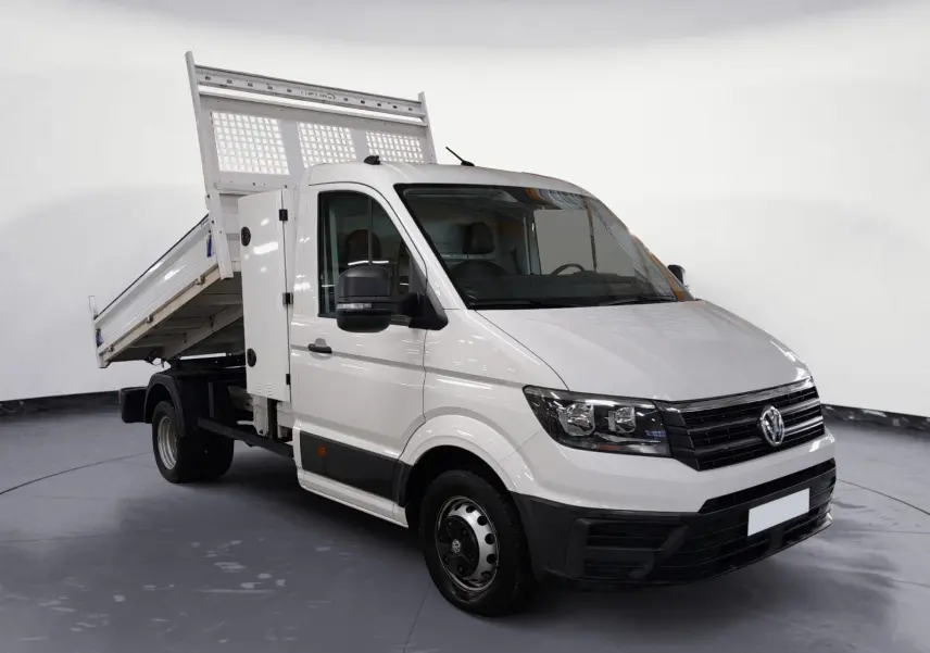Vue 3/4 avant droite d’un Volkswagen Crafter blanc avec benne relevée, coffre latéral et roues jumelées arrière.