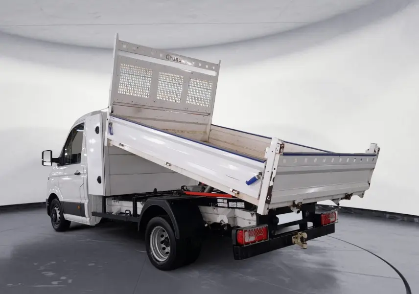 Volkswagen Crafter blanc en 3/4 arrière droit avec benne relevée et coffre, roues jumelées visibles.