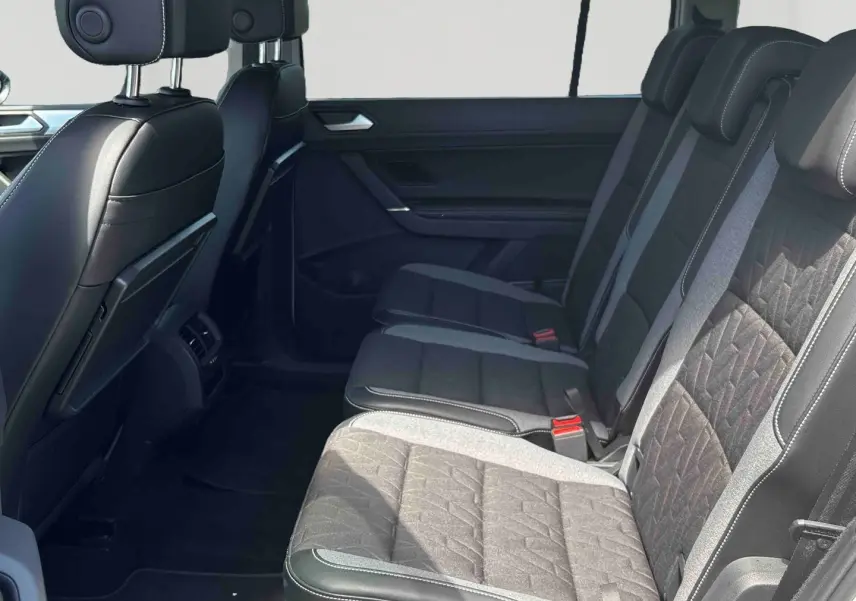 Vue latérale intérieure sur la banquette arrière noire et grise du Volkswagen Touran 2025 avec appuie-têtes ajustables.