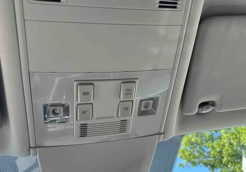 Plafonnier intérieur gris clair avec commandes d’éclairage et pare-soleil partiel du Volkswagen Touran blanc, vue de dessous.
