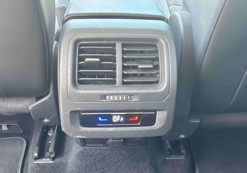 Vue rapprochée de la console arrière du Volkswagen Touran blanc 2025, montrant les aérateurs et commandes de climatisation.