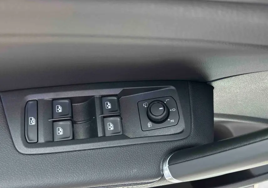 Gros plan sur les commandes des vitres et rétroviseurs côté gauche intérieur du Volkswagen Touran blanc.