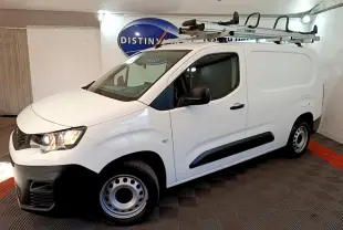 Vue 3/4 avant droite du Peugeot Partner blanc avec galerie de toit et jantes acier en intérieur fermé.