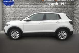 Profil côté gauche d'un Volkswagen T-Cross blanc 2020 avec jantes alliage et protections noires sur les passages de roues.