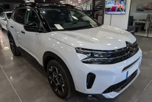 Vue 3/4 avant droit du Citroën C5 Aircross 2025 blanc Okénite avec toit noir et jantes noires en concession.