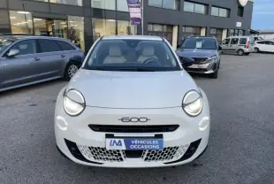 Vue de face d'une FIAT 600 blanche 2025 avec phares allumés et logo 600 visible sur la calandre.