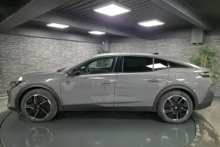 Profil droit de la Peugeot 408 gris Selenium 2024 hybride rechargeable avec jantes alliage 19 pouces et vitres teintées.