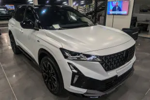 Renault Austral blanc nacré satin avec toit noir, vu en 3/4 avant droit, mettant en valeur sa calandre et ses phares LED.