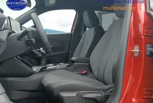 Vue intérieure côté conducteur de la Peugeot 2008 rouge elixir, mettant en valeur les sièges en tissu gris et la console centrale.