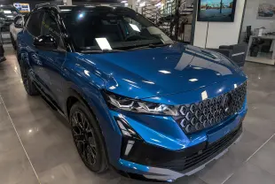 Vue 3/4 avant droit du Renault Austral 2025 bleu outremer avec toit noir et calandre hexagonale distinctive.