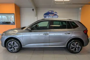 Vue latérale droite d'un Skoda Kamiq gris graphite métal 2025 en intérieur, avec jantes alliage et toit ouvrant.