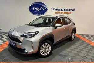 Toyota Yaris Cross gris minéral vue 3/4 avant droit en intérieur avec jantes alliage et feux allumés.