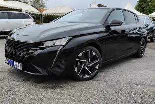 Peugeot 308 PureTech 130 Allure Pack noire vue en 3/4 avant droit avec jantes bi-ton et calandre noire brillante.