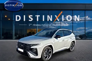 Vue 3/4 avant droite d'un Hyundai Tucson gris shadow avec calandre noire et jantes alu noires devant un showroom Distinxion.