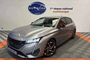 Peugeot 308 gris en 3/4 avant droit, phares LED allumés et jantes alliage distinctives, en showroom.