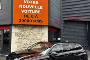 Peugeot 308 PureTech 130 noire vue en 3/4 avant droit devant un bâtiment avec panneau orange Distinxion.