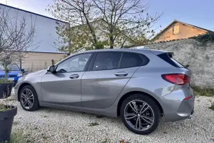 BMW Série 1 gris foncé vue de profil côté gauche, soulignant ses jantes alliage et lignes dynamiques.