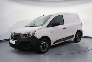 Vue 3/4 avant droite d’un Renault Kangoo blanc 2024 avec pare-chocs noir et calandre chromée, stationné sur un sol gravillonné.
