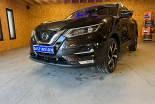 Vue 3/4 avant droit d'un Nissan Qashqai noir avec jantes alliage et calandre chromée dans un garage en bois.