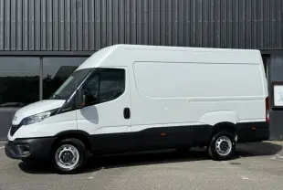 Vue de profil côté gauche d’un utilitaire Iveco Daily blanc avec bas de caisse noir, sans marquages, sur fond industriel.