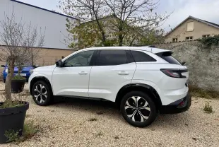 Renault Austral blanc en vue profil côté gauche, stationné sur gravier avec jantes noires et toit noir contrasté.