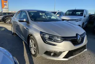 Renault Mégane Sedan gris platine vue 3/4 avant avec projecteurs antibrouillard et calandre noire brillante.