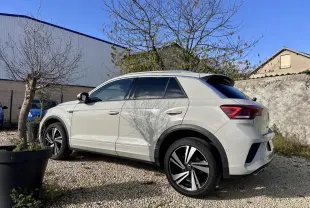Volkswagen T-Roc gris clair vu de profil côté gauche, avec jantes alliage noires et toit contrasté noir.