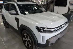 SUV Dacia Duster Hybrid-G blanc Glacier vu en 3/4 avant droit, avec jantes noires et détails noirs contrastants.