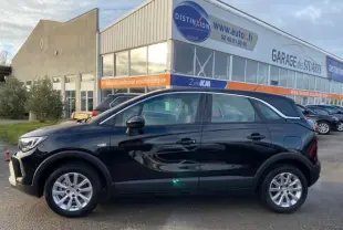Opel Crossland noir métal vue de profil côté gauche, stationné devant un garage avec vitres teintées et jantes argentées.