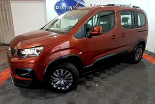 Peugeot Rifter BlueHDi 100 marron en 3/4 avant droit, avec barres de toit chromées et protections noires sur les bas de caisse.