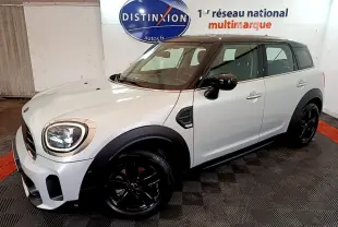 Vue 3/4 avant droit d'une MINI Countryman gris clair avec toit noir et jantes noires dans un showroom.