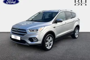 Ford Kuga gris lunaire en 3/4 avant droit, mettant en valeur ses jantes alu et son design moderne.