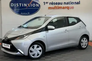 Toyota Aygo gris clair vue de profil côté gauche, soulignant son design compact et moderne en intérieur showroom.