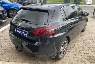 Vue 3/4 arrière droite d'une Peugeot 308 gris hurricane avec vitres arrière surteintées et feux arrière rouges.