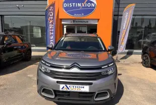 Vue avant d'un Citroën C5 Aircross gris 2019, avec calandre distinctive et toit ouvrant visible, devant un bâtiment orange.