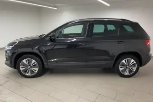 Profil côté gauche du SUV SKODA KAROQ 2023 en noir Magic nacré, avec jantes modernes et feux arrière allumés.