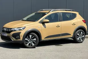 Vue latérale droite d'une Dacia Sandero Stepway beige Safari avec barres de toit et jantes distinctives.